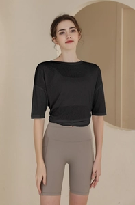 Detail of loose black sports T-shirt with twist-front hem and grey high-waist yoga shorts