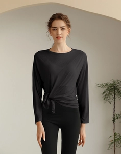 Détail du haut de yoga noir à manches longues avec nœud latéral élégant et tissu respirant