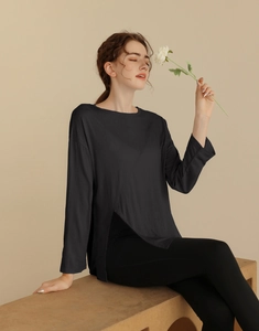 Détail du haut de yoga noir avec ourlet croisé élégant et manches longues respirantes