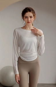 Detail of loose-fit white tencel yoga top showing sheer fabric and pleated hemline detail