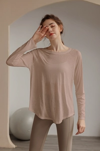 Detail view of light pink long sleeve yoga top featuring breathable fabric and curved hem