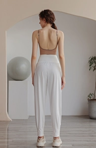Rear view of woman in white high-waisted joggers and brown backless sports top