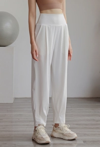 Detail of high-waisted white nylon joggers showing waist compression and elastic cuffs