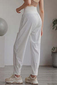 Detail view of high-waist white sports pants with tapered cuffs and quick-dry fabric