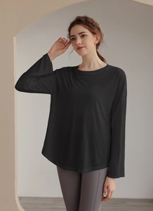 Detail of loose black athletic long-sleeve top with curved hem and crew neck