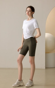Détail du t-shirt de yoga blanc avec fronces latérales et short de fitness vert olive