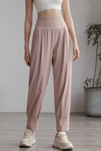 Detail of high-waist light pink nylon joggers with moisture-wicking fabric and elastic cuffs