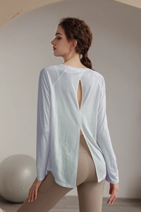 Detail view of white yoga top featuring a breathable open back and split hem design
