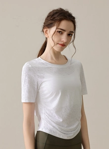 Détail du tissu blanc dévoré sur un t-shirt de yoga ajusté avec fronces latérales