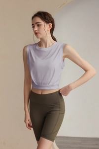 Detail of lavender sleeveless cropped tank top and olive high-waist yoga shorts with pockets
