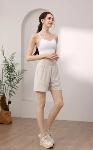Women's activewear set with white cross-strap sports bra and beige high-waisted shorts