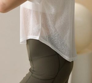 Detail von transparentem weißem Oberteil und olivgrüner Yoga-Leggings mit Seitentaschen