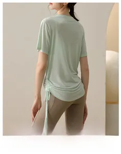 Detail view of adjustable side drawstring and ruched design on light green yoga shirt