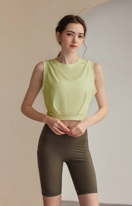Detail view of lime green sleeveless workout top with ruched hem and olive high-waist shorts