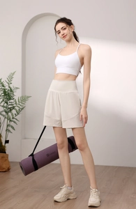 Detail of high-waisted beige nylon yoga shorts with breathable fabric and athletic curved hem