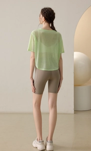 Leichtes mintgrünes Mesh-Yoga-Top mit khakifarbenen Radlershorts und Sneakern