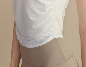 Detail showing the side ruched drawstring and jacquard texture of the white yoga tank top