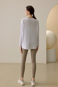 Rear view of a loose long sleeve yoga top with a stylish curved hem and athletic fit leggings
