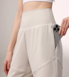 Detail of high-waisted nylon sports shorts with a side pocket holding a smartphone