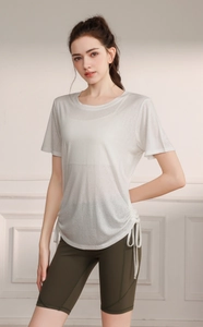 Detail of white translucent yoga top with side drawstring hem and green cycling shorts