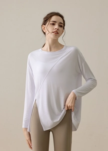 Detail of white long sleeve yoga top featuring side slits and decorative stitching