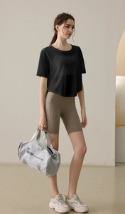 Detail von lockerem Yoga-Oberteil mit High-Waist-Radlerhose und runder Sporttasche