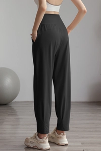 Detail view of high-waisted black nylon yoga pants with wide waistband and cuffed ankles