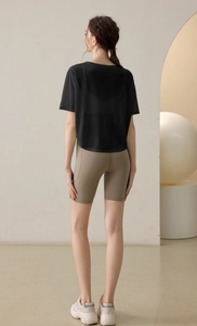 Rückansicht von dünnem schwarzem Yoga-Top und Khaki Fitness-Shorts mit hoher Taille