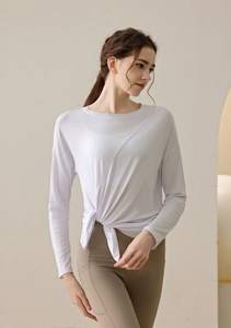 Detail of white yoga long sleeve top featuring unique side knot tie and soft draped texture