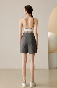 Rear view of woman wearing high-waisted dark grey yoga shorts and a white sports bra