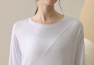 Detail of white yoga long sleeve top featuring asymmetrical seam lines and soft knit texture