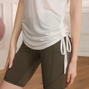Detail view of white drawstring yoga top with olive green high-waisted gym shorts