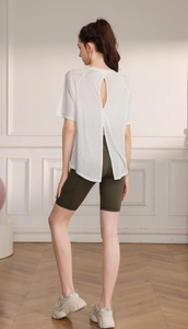 Back view of a white breathable yoga tee with split open back and green cycling shorts