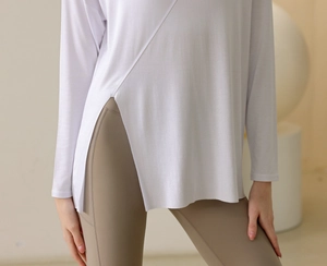 Detail of white yoga long sleeve top with stylish side slit and brown high-waist leggings