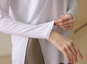 Detail of white yoga long sleeve top with crossover hem and split side design features