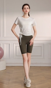 Detail of white short sleeve yoga top with side drawstring and olive green biker shorts