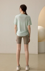 Detail of mint green yoga t-shirt with side drawstring and dark brown cycling shorts