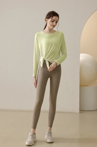 Detail of light green yoga top with knot design and high waist brown leggings with pockets