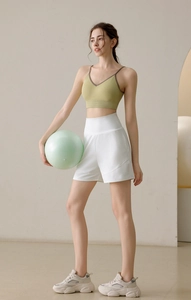 Close-up of high-waist white fitness shorts and green V-neck sports bra on model