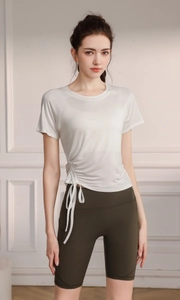 Detail of the side drawstring adjustment on a creamy white breathable yoga workout top