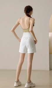 Rear view of loose white high-waist sports shorts paired with a yellow ribbed sports bra