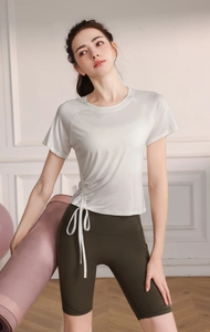 Detail of white yoga top with side drawstring ties and green fitness cycling shorts