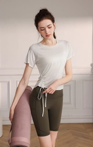 Detail of cream yoga t-shirt with side drawstring and olive green high-waist cycling shorts