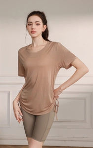 Detail of adjustable side drawstring on light brown yoga top with green cycling shorts