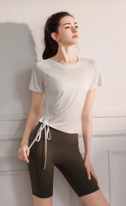 Detail of drawstring pleated side on cream yoga t-shirt and green high-waist shorts