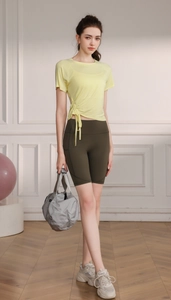 Detail of light yellow yoga top with side drawstring design and green cycling shorts
