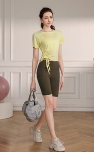 Detail of light yellow yoga top with side drawstrings and olive green cycling shorts