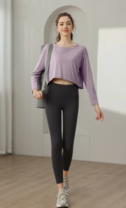 Détail du haut court de sport violet ample porté avec un legging de yoga par le modèle