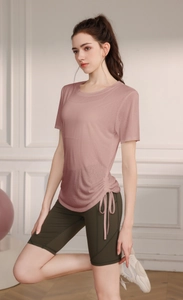 Detail view of pink yoga T-shirt with side drawstring and dark green cycling shorts