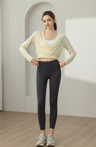 Pale yellow wrap-style yoga top with white sports bra and dark grey high-waist leggings